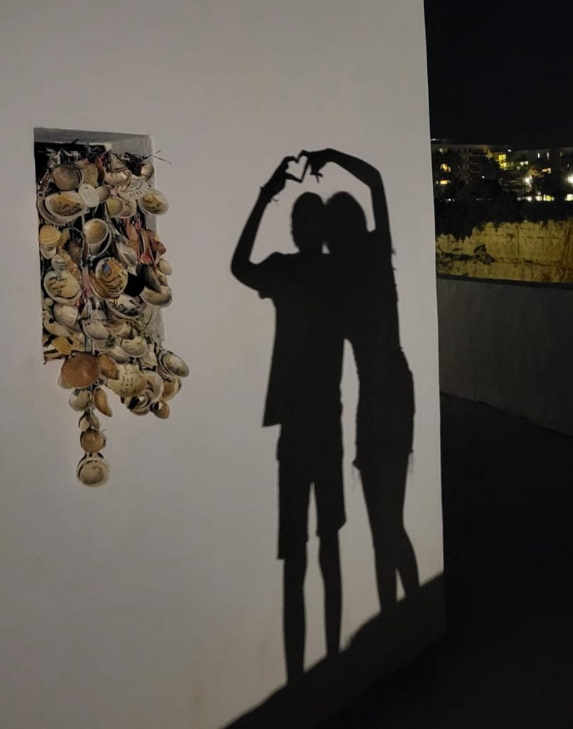 Shadows of two people forming a heart with their hands