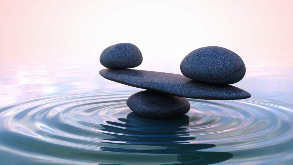 Stacked stones balanced over rippling water symbolising calm and stress relief.