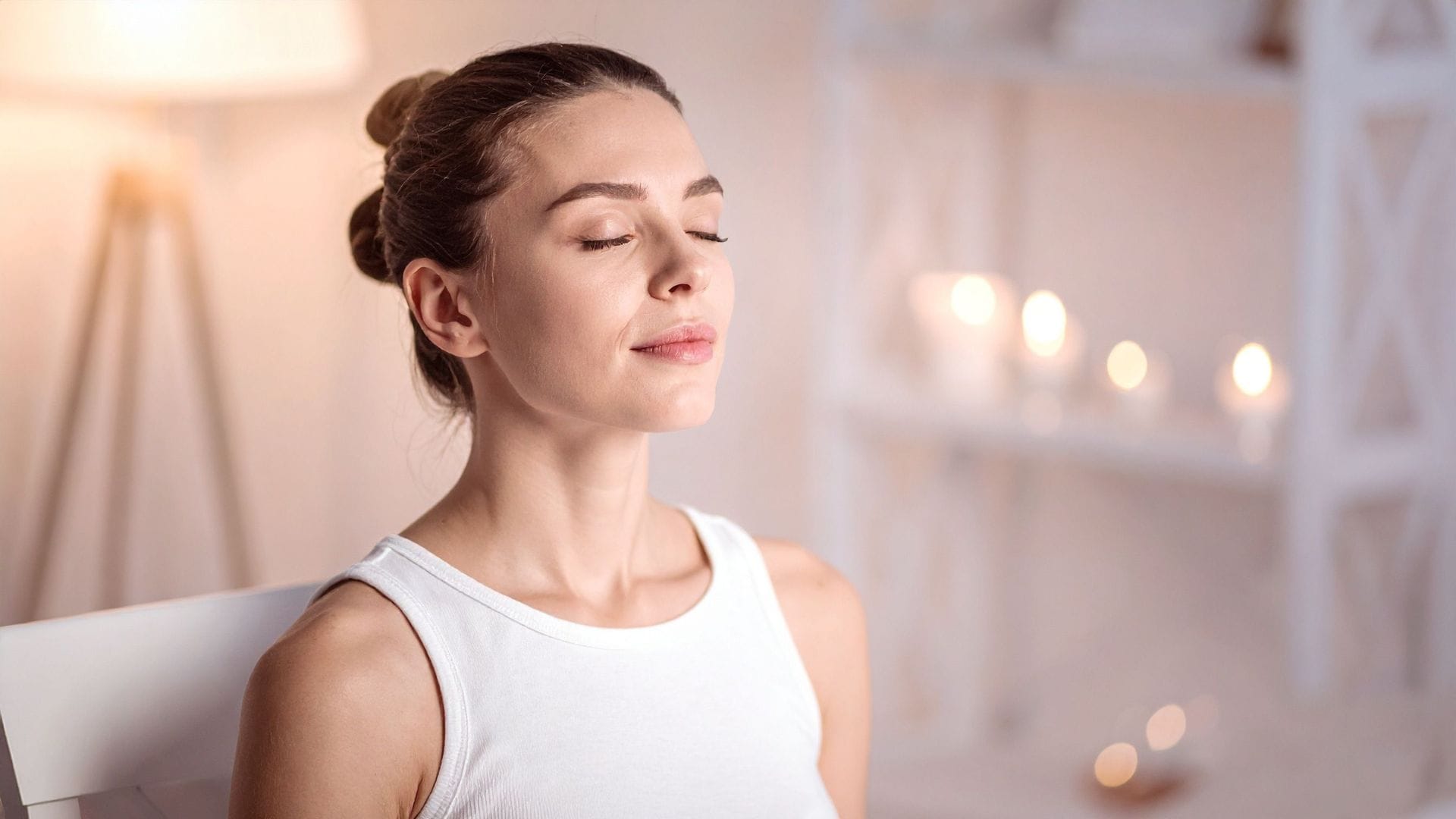 A woman sitting calmly with eyes closed, practising mindful breathing in a peaceful setting.